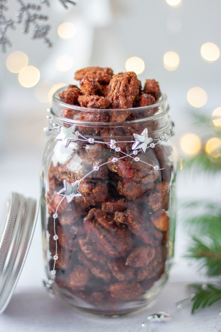 Gingerbread Candied Nuts in a jar in front of Christmas lights