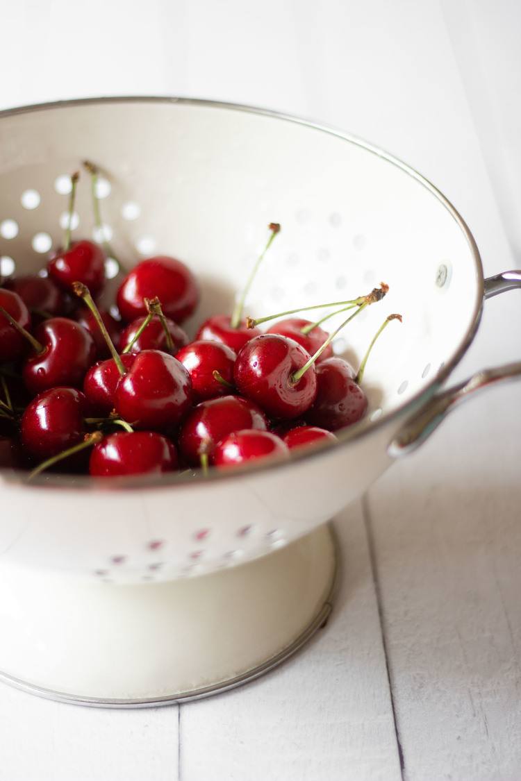 fresh cherries in a white sieve